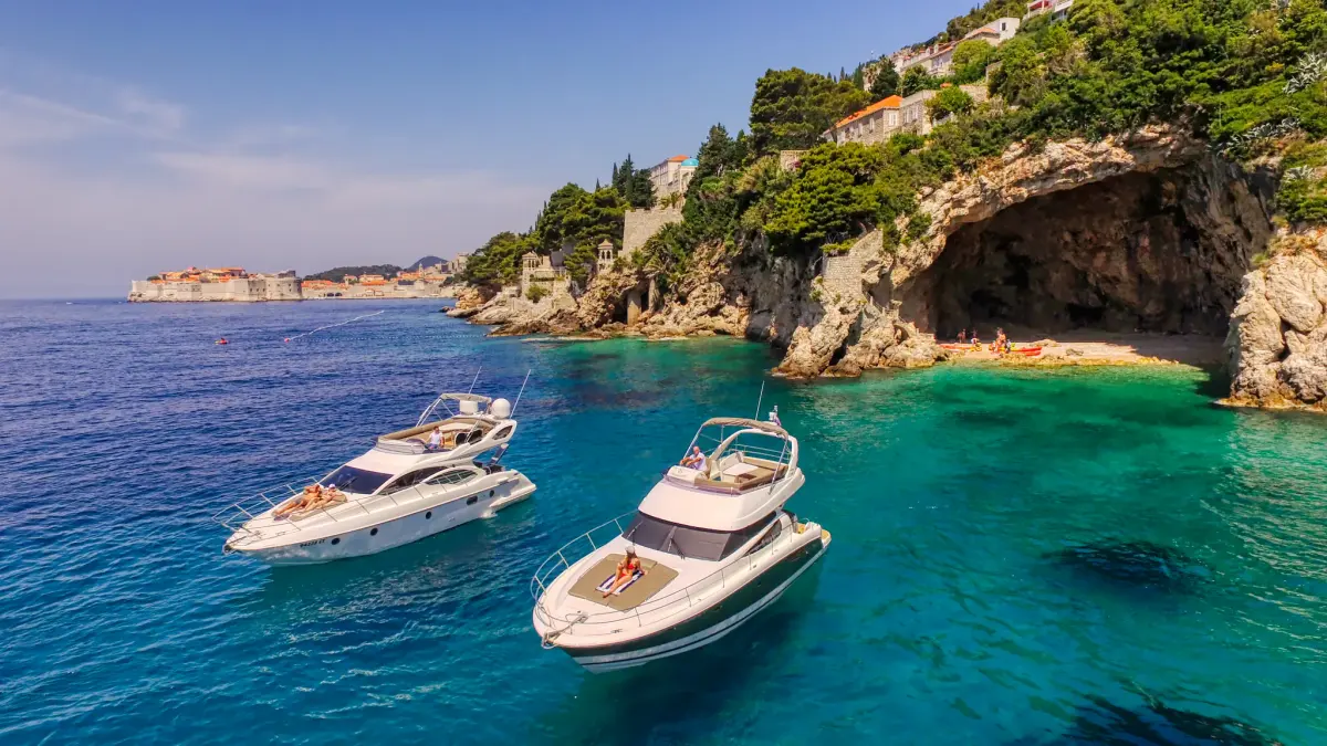 Two motor yachts anchored in a turquoise cove near Dubrovnik