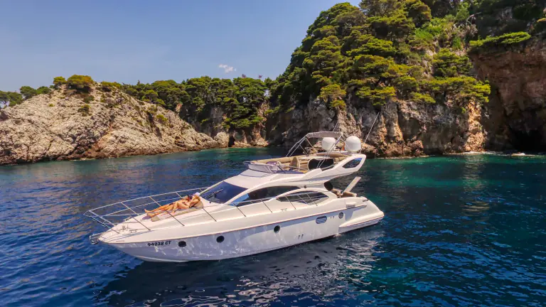Aphrodite anchored below green cliffs