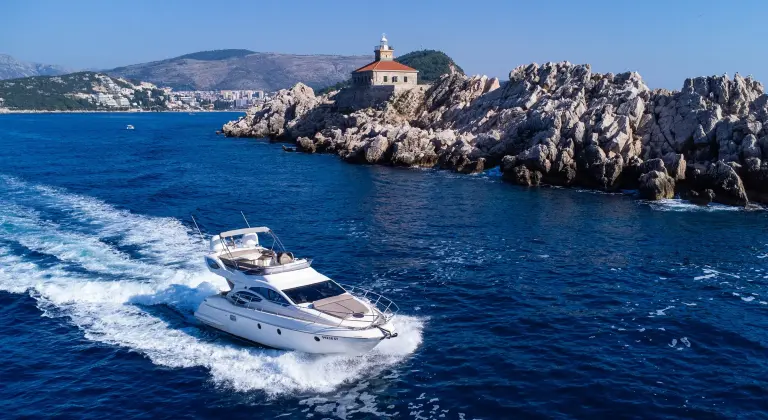 Aphrodite passing a rocky islet with a lighthouse