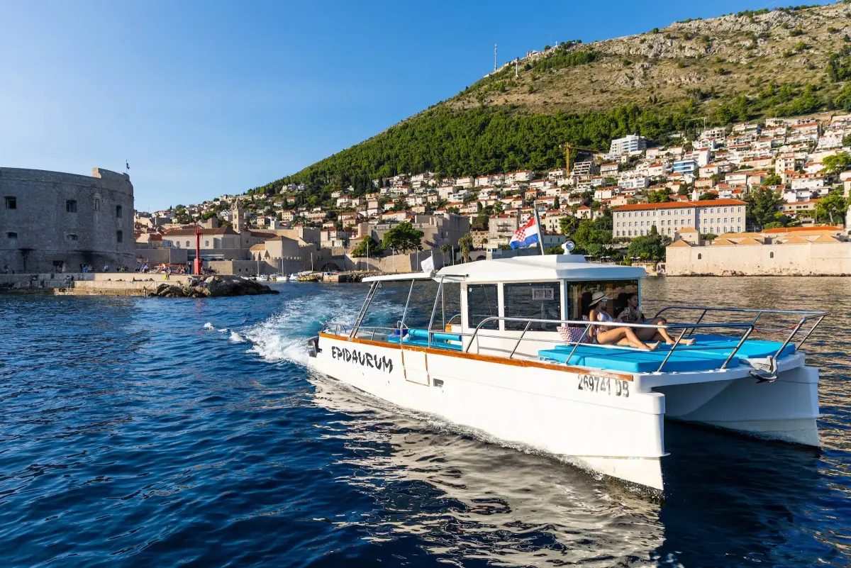 Double-deck catamaran cruising past Dubrovnik Old Town