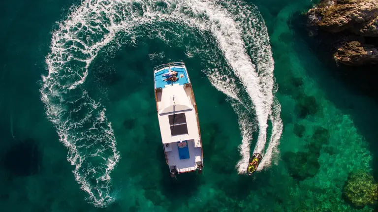 Speedboat carving a turn in turquoise water, seen from above