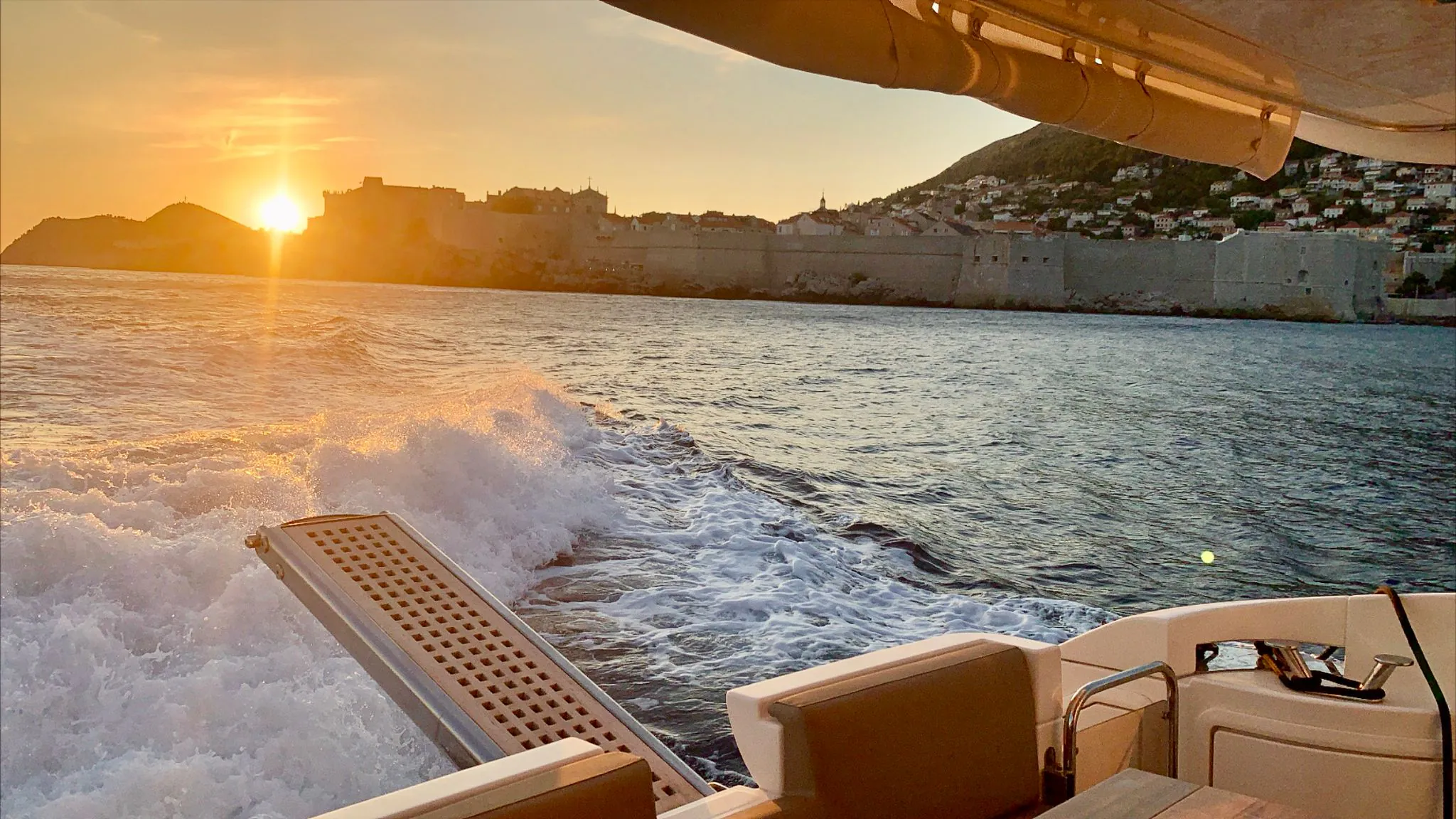 Sunset over the islands from the stern of a moving boat