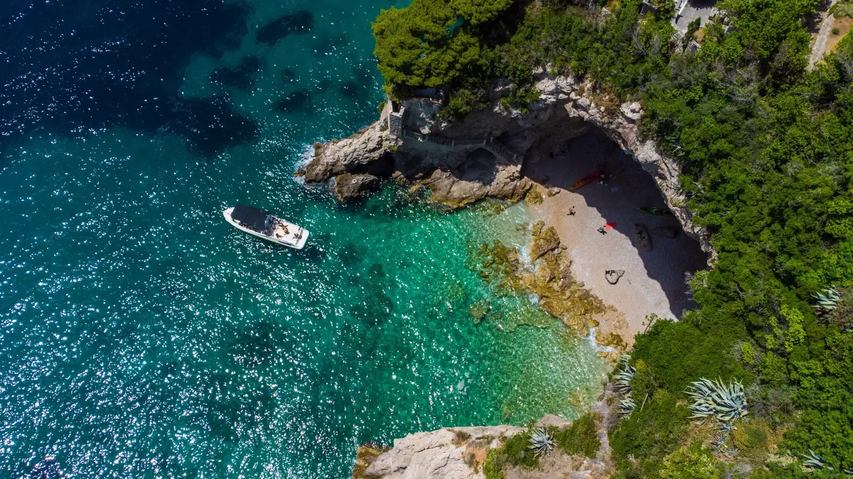 Boat anchored in a quiet turquoise cove beneath white cliffs