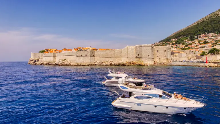 Yachts cruising together in front of Dubrovnik Old Town