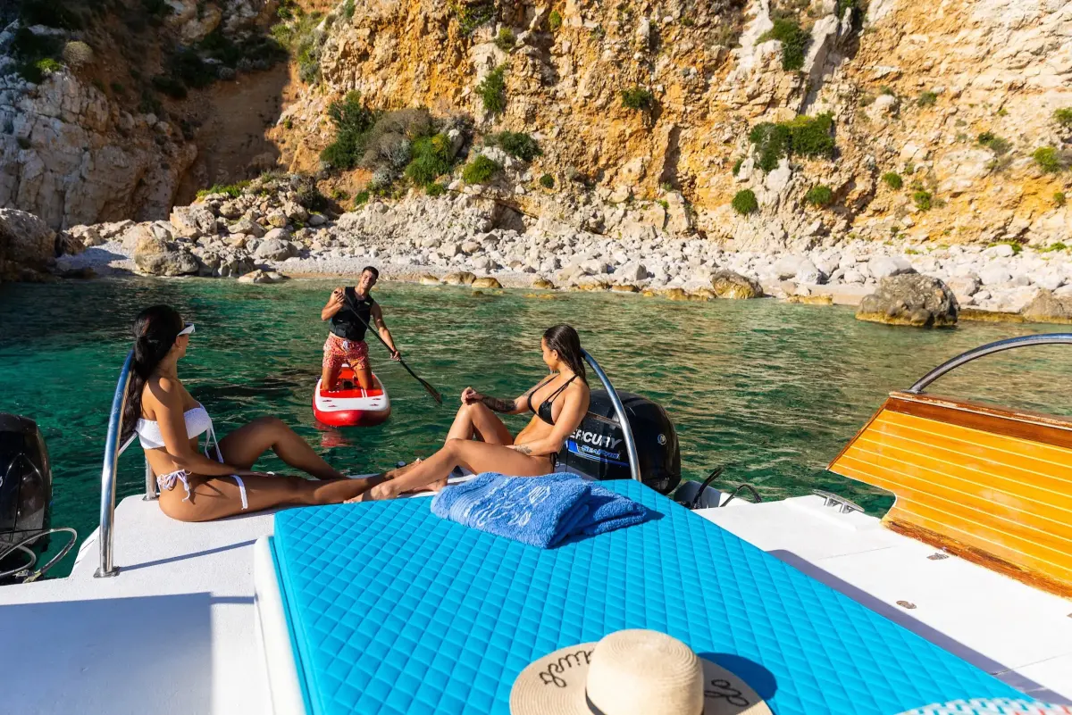 Guests relaxing on the sun deck of a boat in a rocky cove
