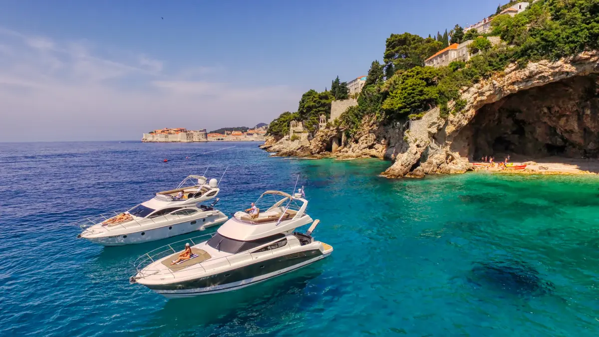 Guests sunbathing on a boat bow in front of a sea cave