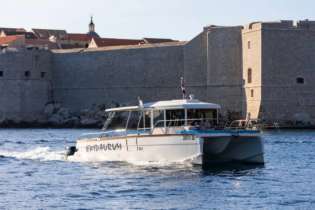 Epidaurum catamaran leaving the Old Port under the city walls