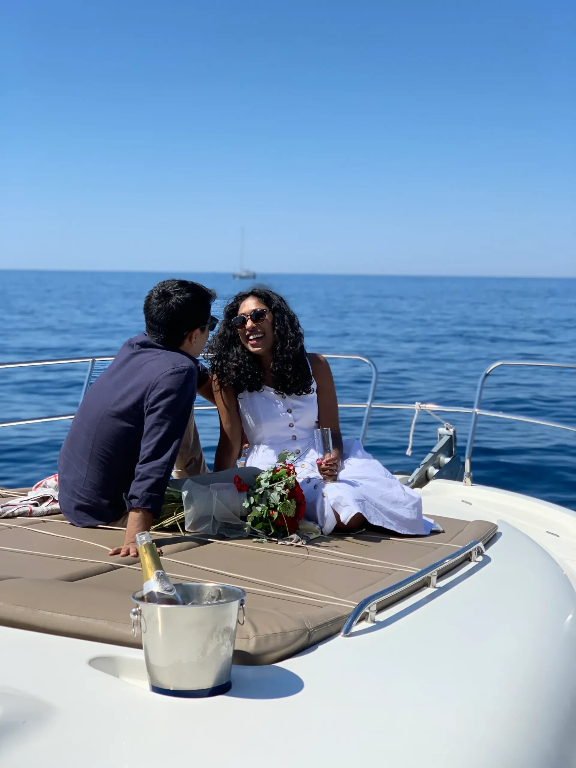 Couple celebrating a proposal on the bow of a yacht