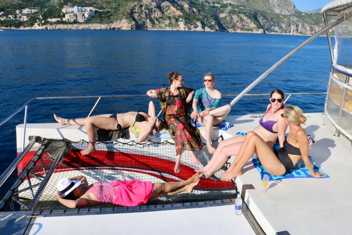 Group of friends relaxing on the catamaran's bow nets