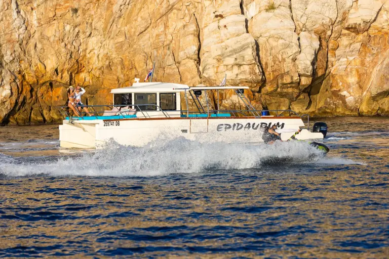 Epidaurum catamaran cruising past golden cliffs