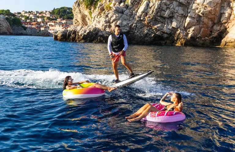 E-board rider and guests on inflatable rings in a cove
